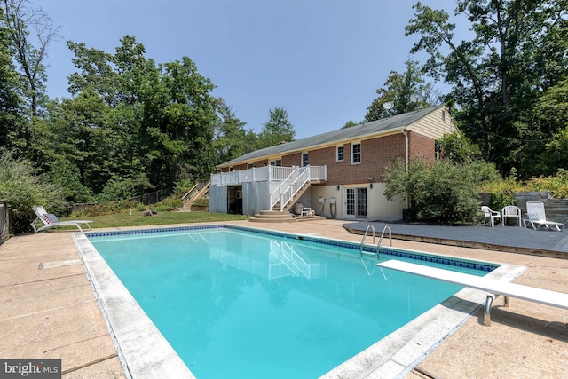 view of pool with a wooden deck, a patio, and a diving board