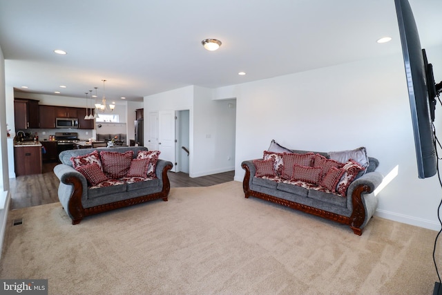 living room featuring sink, a chandelier, and light hardwood / wood-style flooring