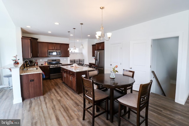 dining space featuring dark hardwood / wood-style flooring, sink, and a notable chandelier