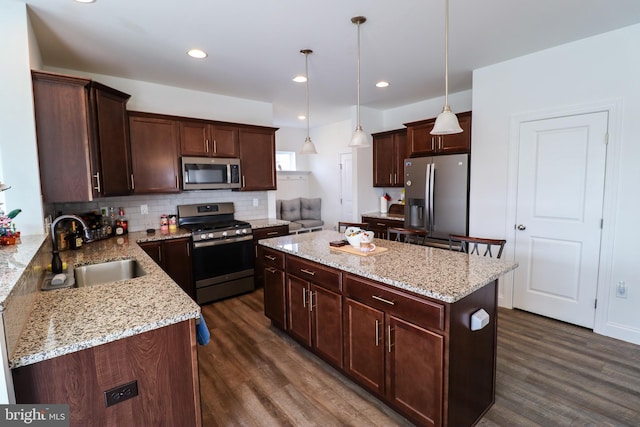 kitchen with dark hardwood / wood-style flooring, pendant lighting, a center island, stainless steel appliances, and sink