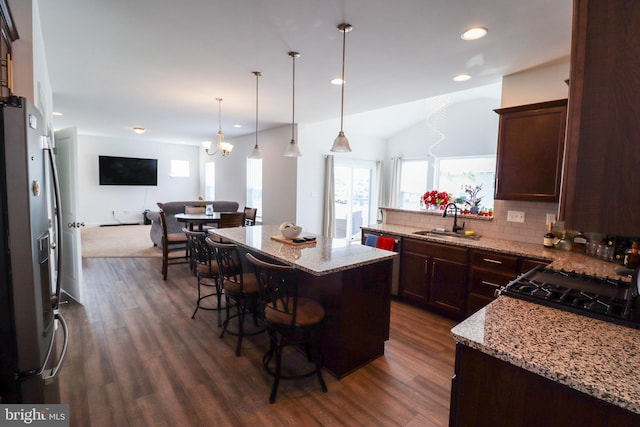 kitchen featuring dark wood-type flooring, a kitchen breakfast bar, a kitchen island, and sink