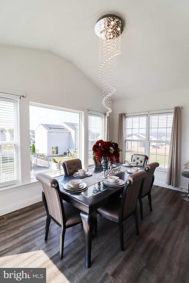 dining area featuring lofted ceiling, hardwood / wood-style flooring, and an inviting chandelier