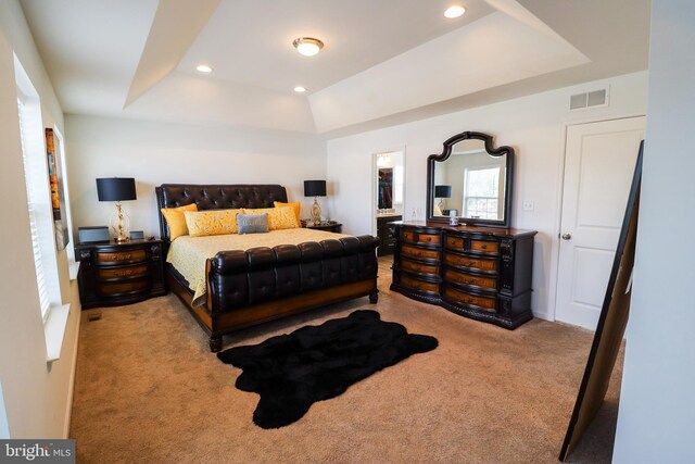 bedroom with light colored carpet and a raised ceiling