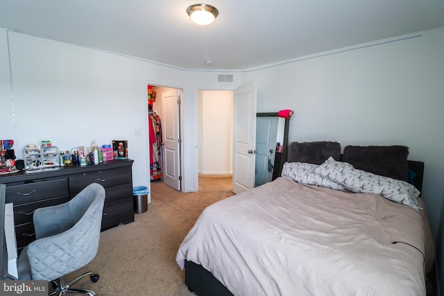 bedroom with light colored carpet and a walk in closet