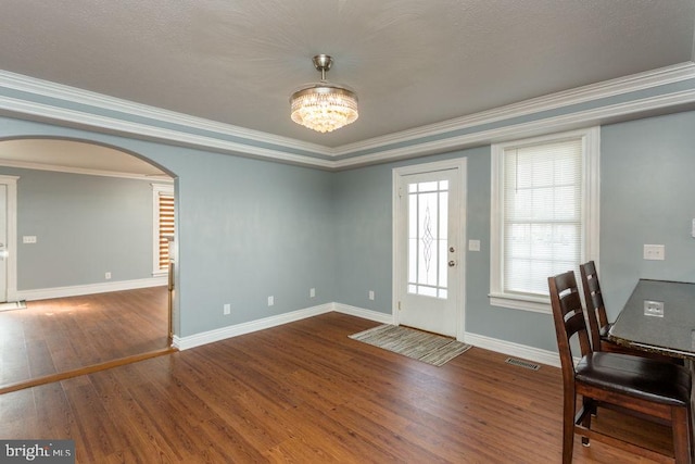 interior space featuring a textured ceiling, crown molding, a notable chandelier, and wood-type flooring