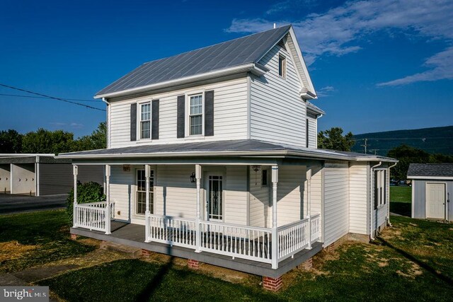 farmhouse inspired home featuring a front yard, covered porch, and a shed