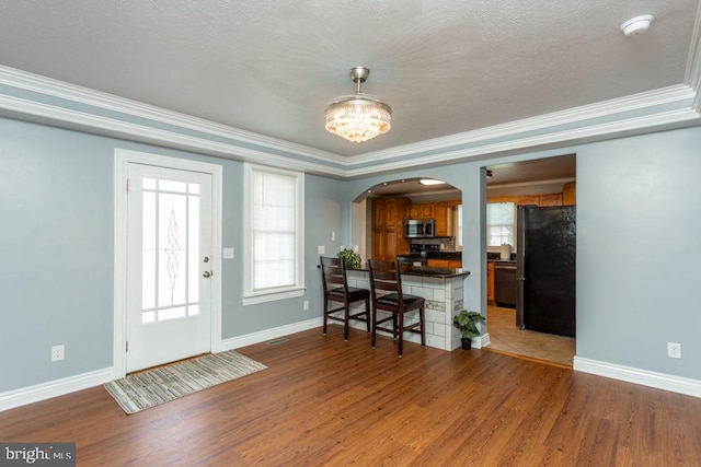 interior space featuring ornamental molding, an inviting chandelier, hardwood / wood-style flooring, and a textured ceiling