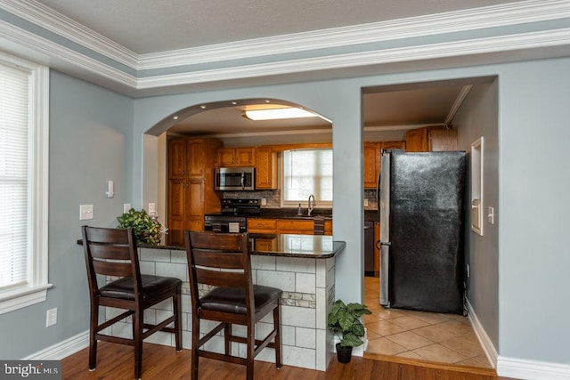 kitchen with crown molding, sink, a breakfast bar, appliances with stainless steel finishes, and light hardwood / wood-style floors