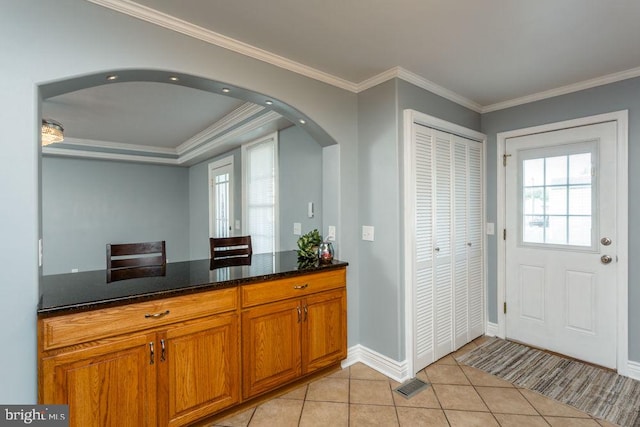 kitchen featuring crown molding, dark stone counters, and light tile patterned flooring