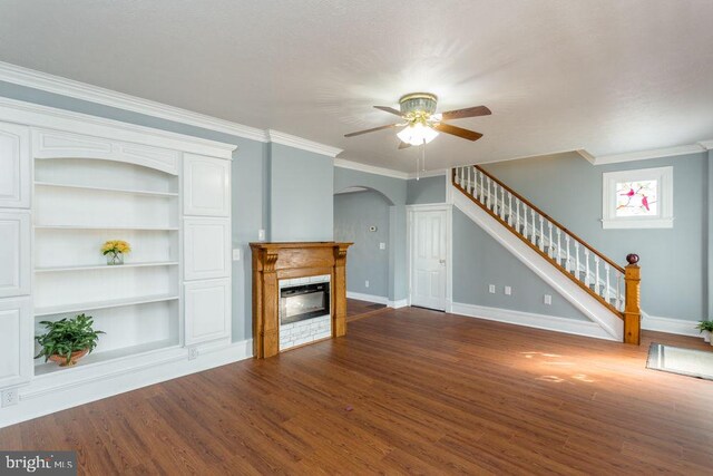 unfurnished living room featuring built in features, crown molding, ceiling fan, and dark hardwood / wood-style flooring