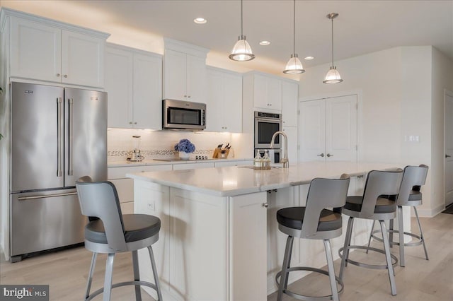 kitchen with light wood-style floors, stainless steel appliances, backsplash, and light countertops