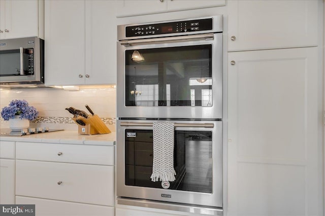 kitchen featuring light stone counters, stainless steel appliances, tasteful backsplash, and white cabinets