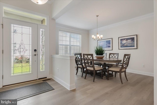 dining space with a chandelier, light wood-style flooring, crown molding, and baseboards