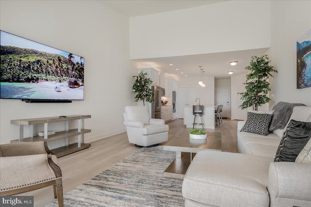 living area with light wood finished floors, a high ceiling, and baseboards