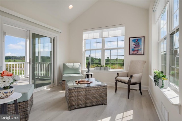 sitting room with light wood-type flooring, lofted ceiling, baseboards, and visible vents