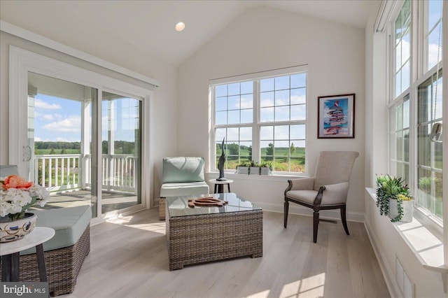 living area with a healthy amount of sunlight, light wood-type flooring, baseboards, and vaulted ceiling