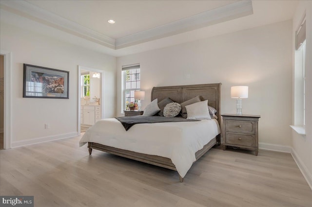 bedroom featuring baseboards, a raised ceiling, light wood-style flooring, and ornamental molding