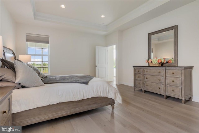 bedroom with a tray ceiling, recessed lighting, light wood-style floors, and baseboards