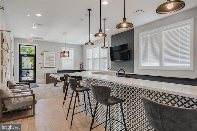 kitchen featuring light wood finished floors, visible vents, hanging light fixtures, and open floor plan