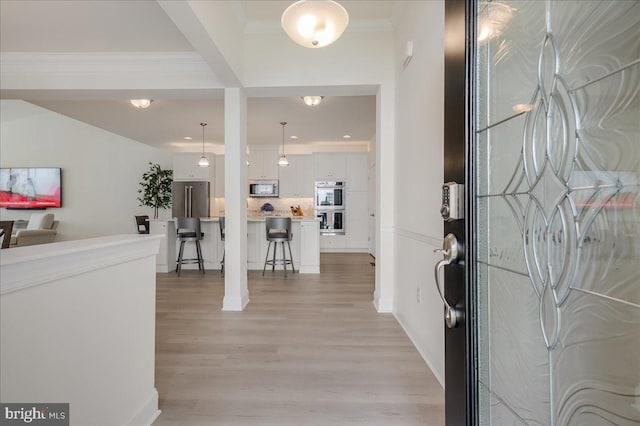 entrance foyer with light wood-style flooring and crown molding