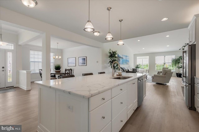 kitchen with open floor plan, a center island with sink, wood finished floors, stainless steel appliances, and a sink