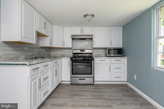 kitchen featuring light wood-type flooring, stainless steel appliances, tasteful backsplash, and white cabinetry