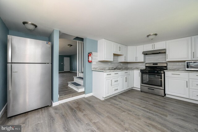 kitchen featuring white cabinets, appliances with stainless steel finishes, sink, and light hardwood / wood-style flooring