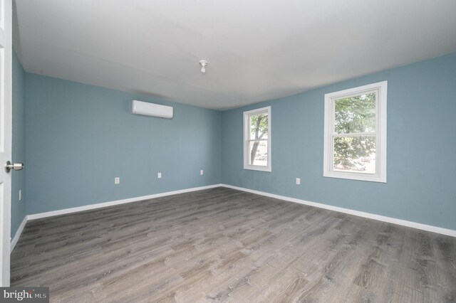 empty room featuring hardwood / wood-style floors and a wall mounted air conditioner