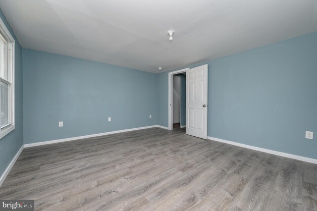 unfurnished room with an AC wall unit and wood-type flooring