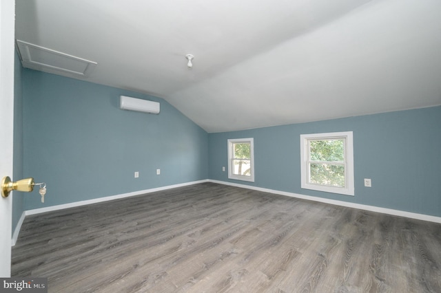 additional living space with lofted ceiling, hardwood / wood-style flooring, and a wall unit AC