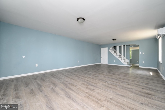 interior space with wood-type flooring and a wall mounted air conditioner