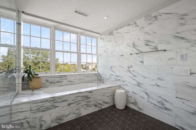 bathroom with tiled bath, tile walls, and tile patterned floors