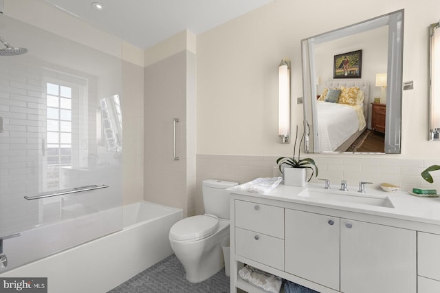 full bathroom featuring tile walls, tiled shower / bath, vanity, and toilet