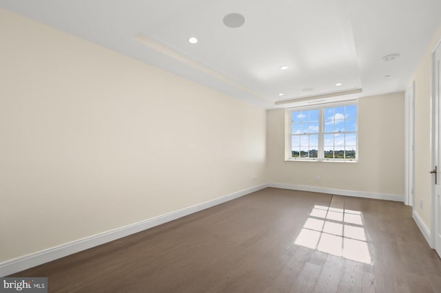 empty room with a raised ceiling and hardwood / wood-style floors