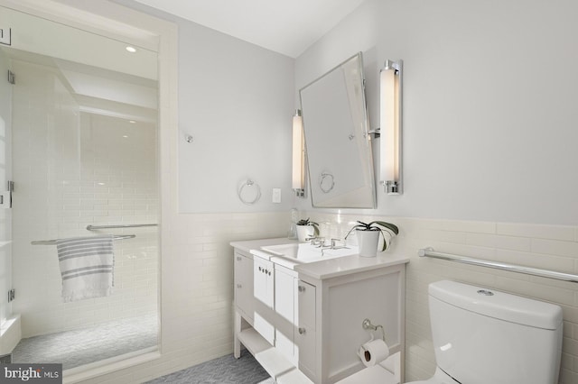 bathroom featuring vanity, tile walls, toilet, and a shower with door