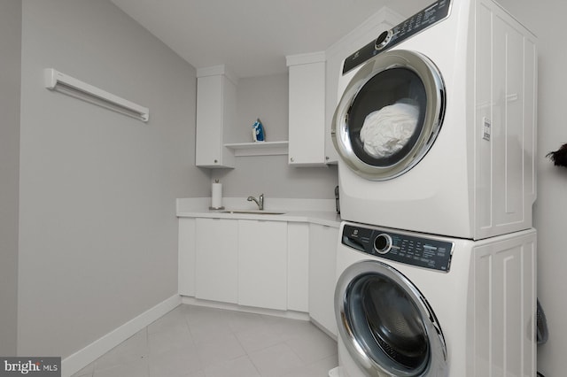 clothes washing area with stacked washer and clothes dryer, cabinets, and sink