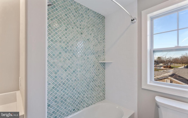 bathroom featuring tiled shower / bath and toilet