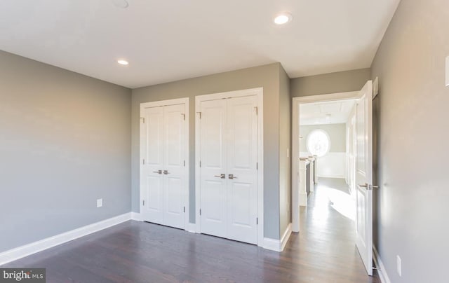 unfurnished bedroom with two closets and dark hardwood / wood-style flooring