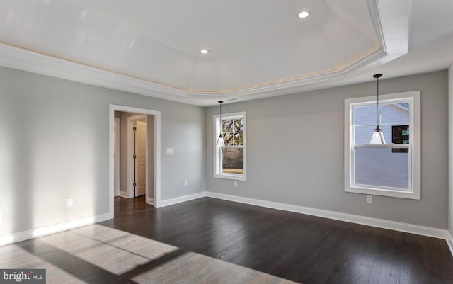 empty room featuring a tray ceiling, dark hardwood / wood-style floors, and ornamental molding