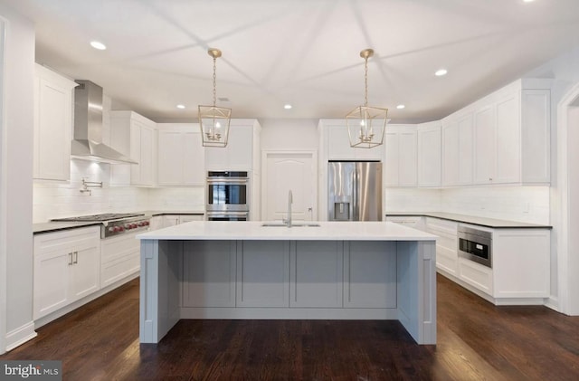 kitchen featuring appliances with stainless steel finishes, white cabinetry, sink, and wall chimney range hood