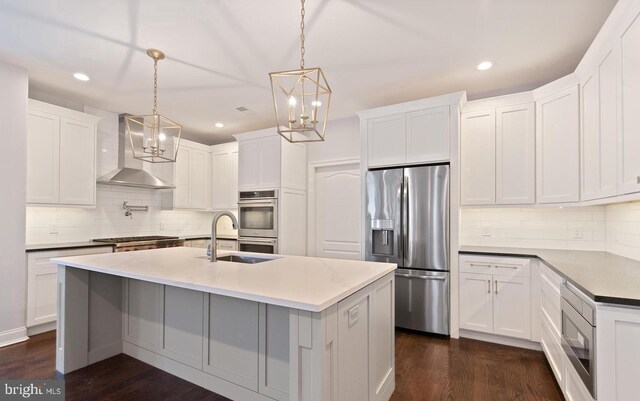 kitchen with dark wood-type flooring, wall chimney range hood, stainless steel appliances, and white cabinets