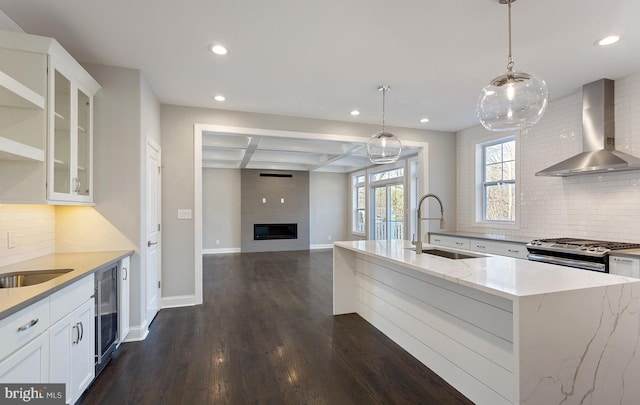 kitchen featuring white cabinets, gas stove, and wall chimney range hood