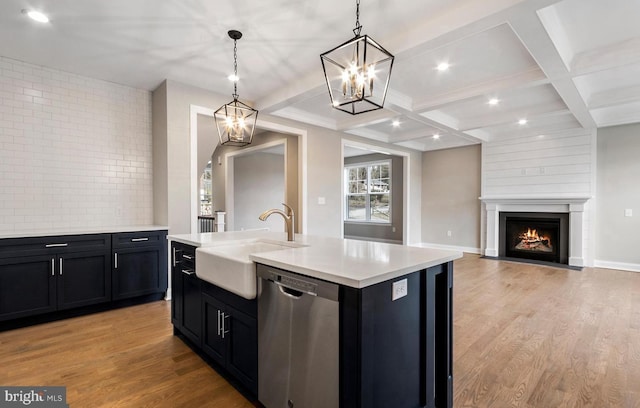 kitchen featuring an island with sink, dishwasher, light wood-type flooring, sink, and a chandelier