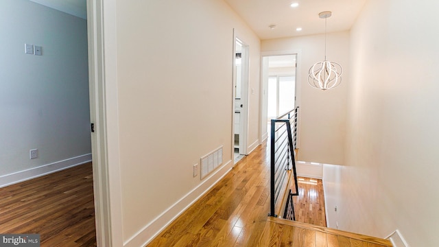 hallway featuring wood-type flooring and a chandelier