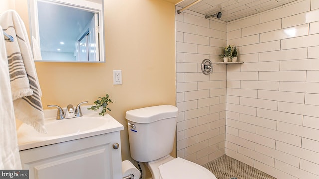 bathroom with tiled shower, vanity, and toilet