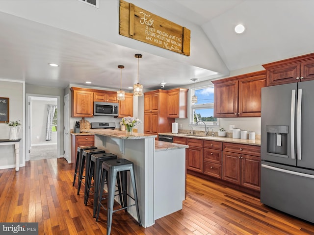 kitchen featuring decorative light fixtures, a kitchen island, light stone countertops, dark wood-type flooring, and appliances with stainless steel finishes