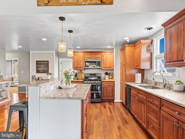 kitchen with a kitchen bar, stainless steel appliances, sink, and light hardwood / wood-style floors