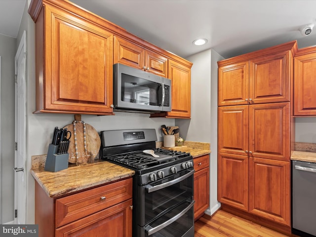 kitchen featuring stainless steel appliances, light stone countertops, and light hardwood / wood-style floors