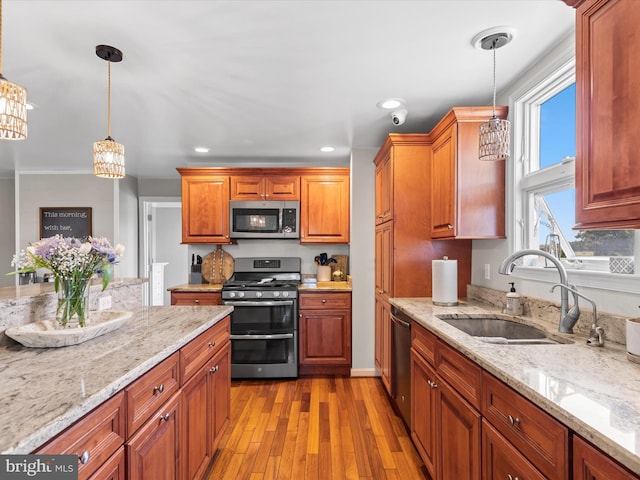 kitchen featuring decorative light fixtures, appliances with stainless steel finishes, light hardwood / wood-style flooring, and sink