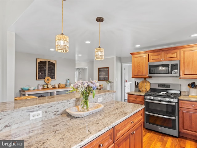 kitchen with stainless steel appliances, light stone counters, a chandelier, and light hardwood / wood-style floors